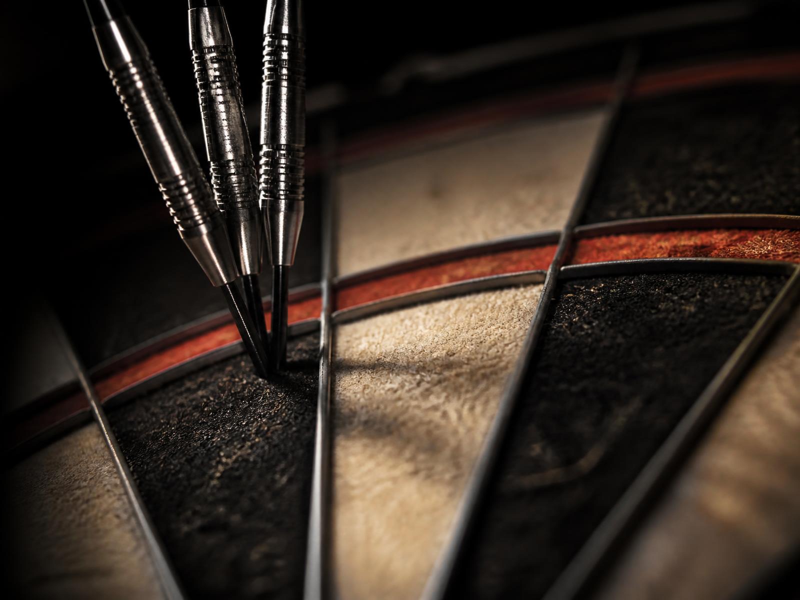 Three darts grouped in the treble twenty of a bristle dartboard