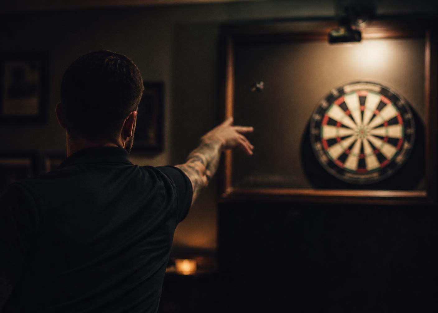 A player throwing at a lit dartboard in a home setup